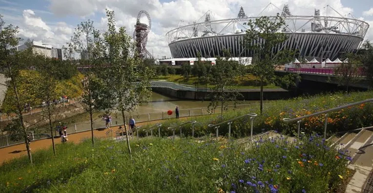 Góc nhìn toàn cảnh London Stadium từ khu vườn xanh mát bên ngoài, thể hiện sự hài hòa với thiên nhiên