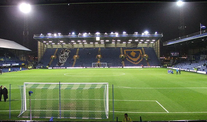 Sân Fratton Park trước một trận đấu đêm, ánh đèn pha đã bật sáng